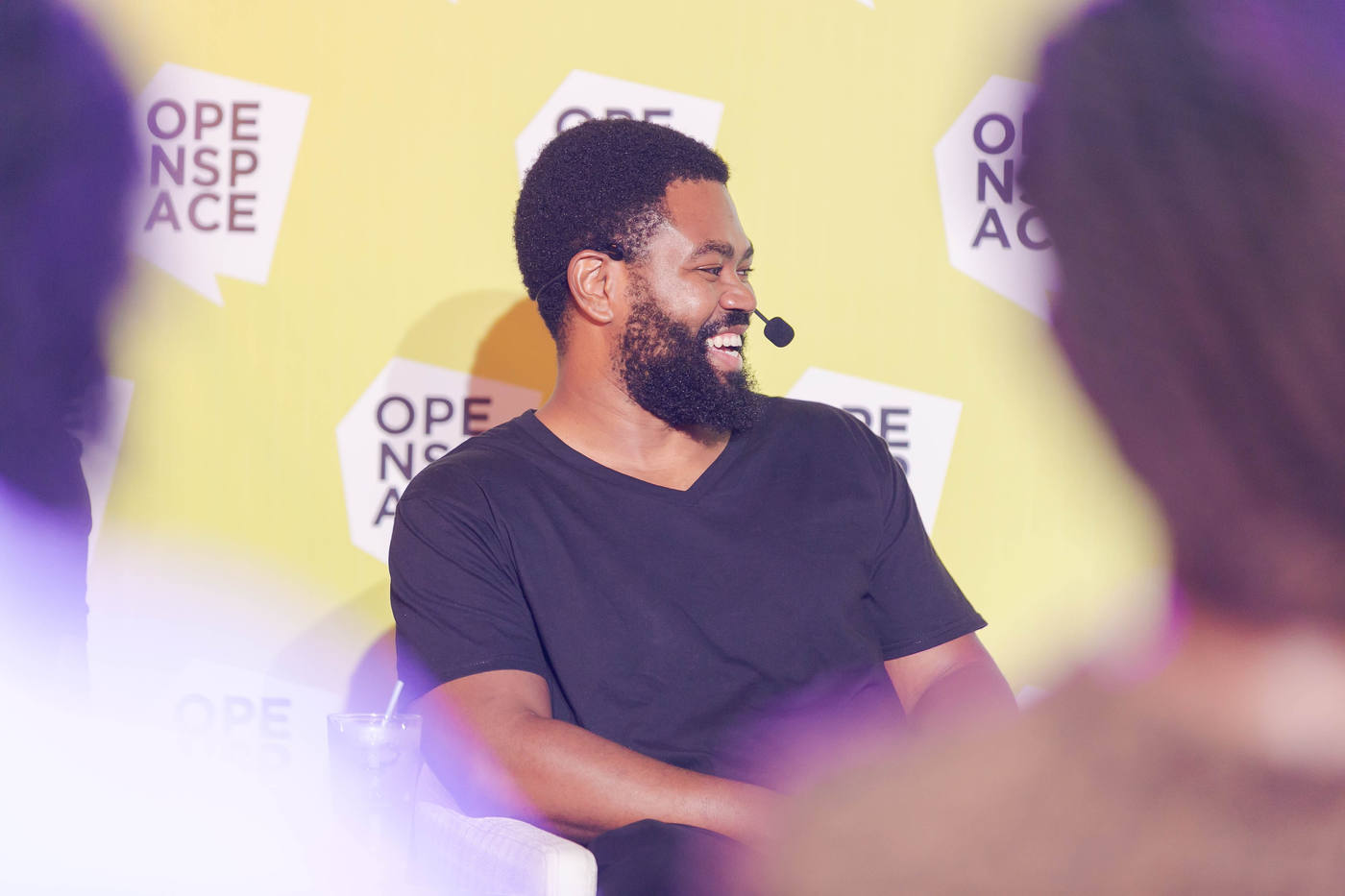 A speaker smiling in front of the OPENSPACE backdrop